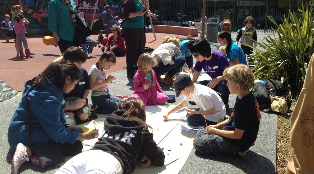 students-outside-painting-mural-with-parental-mentor-guidance