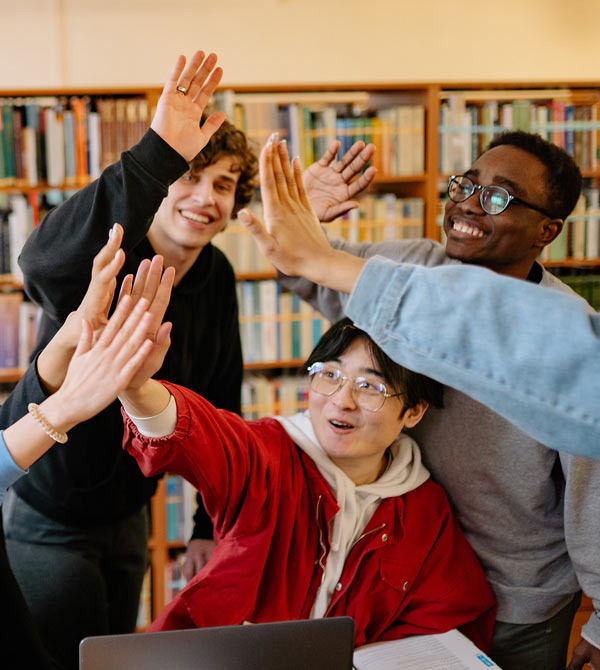 diverse-group-of-young-students-advocates-high-fiving-celebrating-in-library